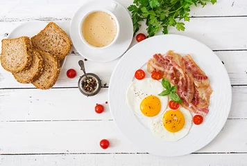 Foto op Plexiglas Spiegeleieren Engels ontbijt - gebakken ei, tomaten en spek. Bovenaanzicht.