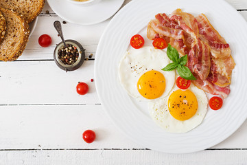 English breakfast - fried egg, tomatoes and bacon. Top view.