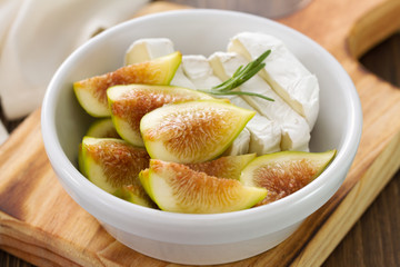figs with cheese in white bowl on wooden background