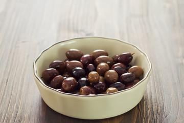 olives in bowl on brown wooden background