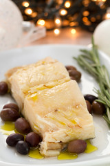 boiled cod fish with oil and olives on white dish
