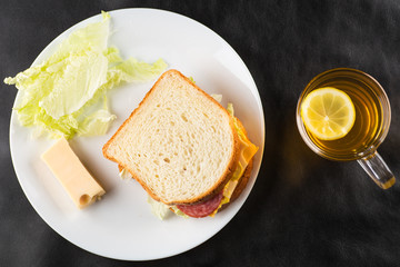Sandwich, cheese sandwich with greens and sausage with tea in the background 