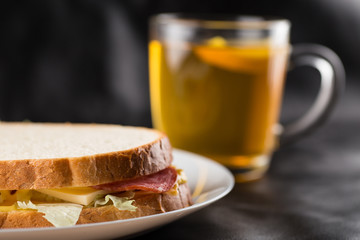 Sandwich, cheese sandwich with greens and sausage with tea in the background 