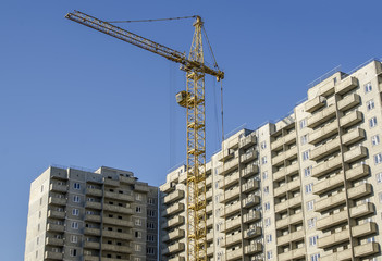 Fototapeta na wymiar Monolithic concrete buildings and the construction crane.