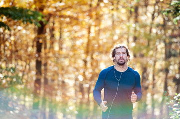 Fototapeta premium Young handsome runner outside in sunny autumn nature