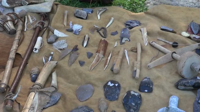 Tools and weapons made of flint and wood placed on animal fur in historic medieval festival