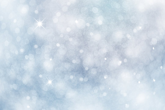 Artistic winter snowfall bokeh background with sparkle. Silver and soft blue colored blurry Christmas and New Year greeting card illustration background with sparkle.