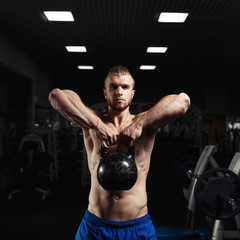 Fototapeta na wymiar Fitness man doing a weight training by lifting heavy kettlebell