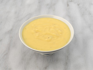 Cheddar potato soup in a bowl on a marble table.