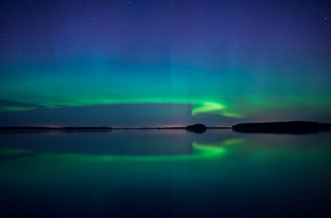 Fototapeta na wymiar Northern lights dancing over calm lake in Sweden