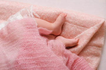 Baby feet newborn. Sleeping baby foots on pink sheet of the bed