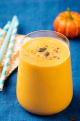 Pumpkin smoothie with pumpkin pie spices on a blue wooden background