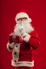 Photo of kind Santa Claus giving xmas present and looking at cam