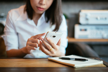 Young woman using smartphone with a notebook.