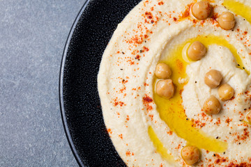 Hummus, chickpea dip, with spices and pita, flat bread in a black plate. Copy space