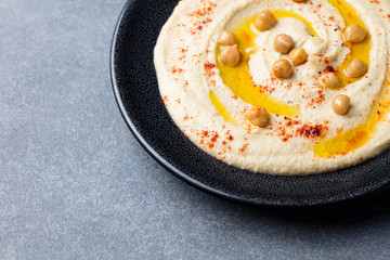 Hummus, chickpea dip, with spices and pita, flat bread in a black plate. Copy space