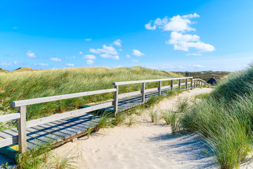 Fototapeta na wymiar Wooden walkway on sand dune to idyllic beach on Sylt island, Germany