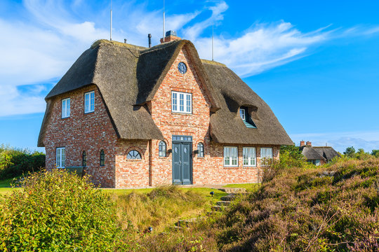 Traditional red brick house with thatched roof in Kampen village on Sylt island, Germany