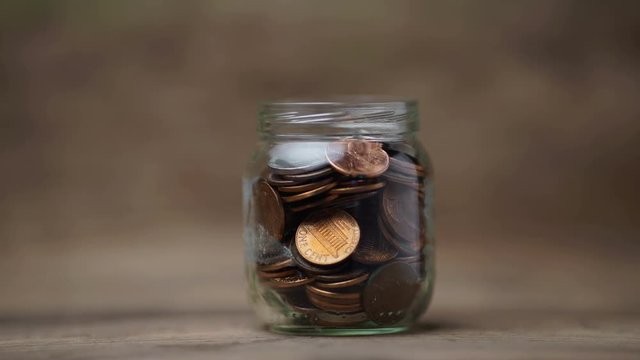 Glass jar being filled with coins, stop motion footage