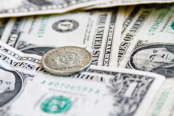 Coin three Cuban pesos over several dollar bills