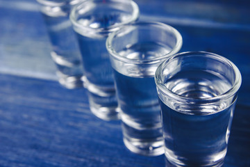 Vodka shots filled with alcohol on wooden blue bar.