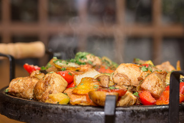 Meat baked with potatoes, vegetables and mushrooms in the pan.