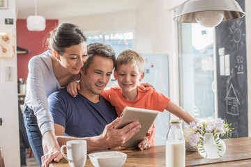 A family using a tablet while having breakfast in the kitchen