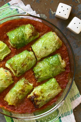 Vegetarische Kohlroulade gefüllt mit Reis, Paprika, Zwiebel und Karotte, serviert auf Tomatensauce, fotografiert mit natürlichem Licht (Selektiver Fokus, Fokus auf die Rouladen)