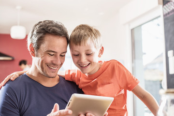 A father and son using a tablet while having breakfast