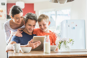 A family using a tablet while having breakfast in the kitchen
