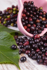 Fresh elderberry with leaf in glass dish on old wooden background