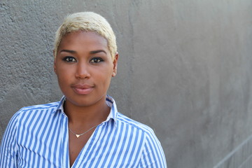 Beautiful young African American woman with short dyed blond hair looking at camera with a relaxed...