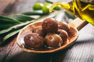 Wooden spoon with olives and olive oil