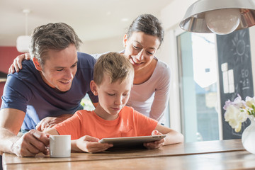 A family using a laptop while having breakfast in the kitchen