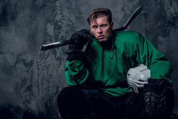 Obraz premium Tired hockey player relaxing on grey background.