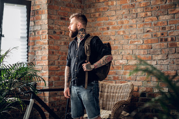 Fototapeta na wymiar Tattooed hipster male in a room with bicycle on background.