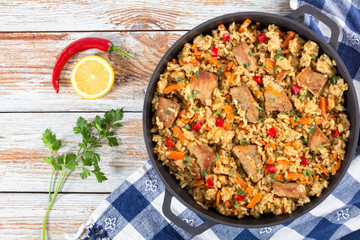paella with meat, pepper, vegetables and spices in iron pan