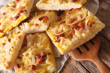 Alsatian onion pie with ham on wooden table. Horizontal
