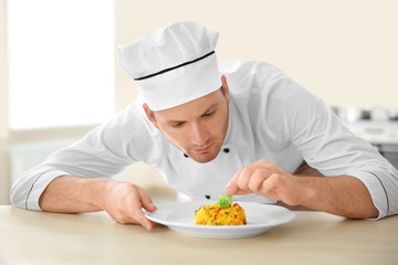 Young chef cook decorating dish in kitchen