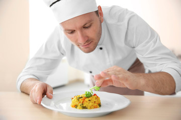 Young chef cook decorating dish in kitchen