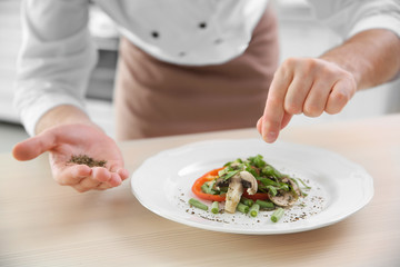 Obraz na płótnie Canvas Chef cook decorating salad with spices, closeup