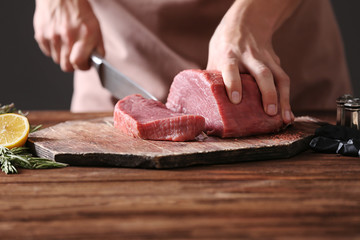 Butcher cutting pork meat on kitchen