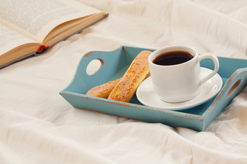 Romantic breakfast in the bed: hot coffee and open book