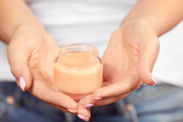 Jar of cream in female hands, close up