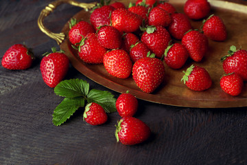 Ripe strawberries on a tray and dark wooden background