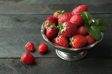 Metal bowl with ripe strawberries on dark wooden background