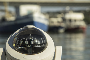 Compass on a boat passing by the anchored ships