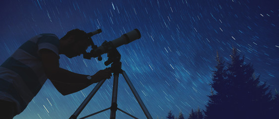 Man looking at the stars with telescope beside him.