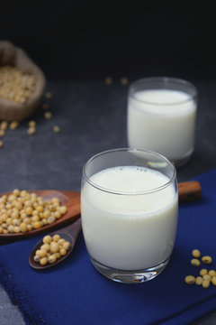 Soy milk in clear glass with soybean seed on wooden spoon and sackcloth bag.