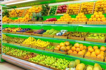 Shelf with fresh organic fruits on a farm market supermarket. Apple, orange, grapes, persimmon, kiwi, pineapple, pear, plum, prunes, melon, watermelon, exotic fruit.